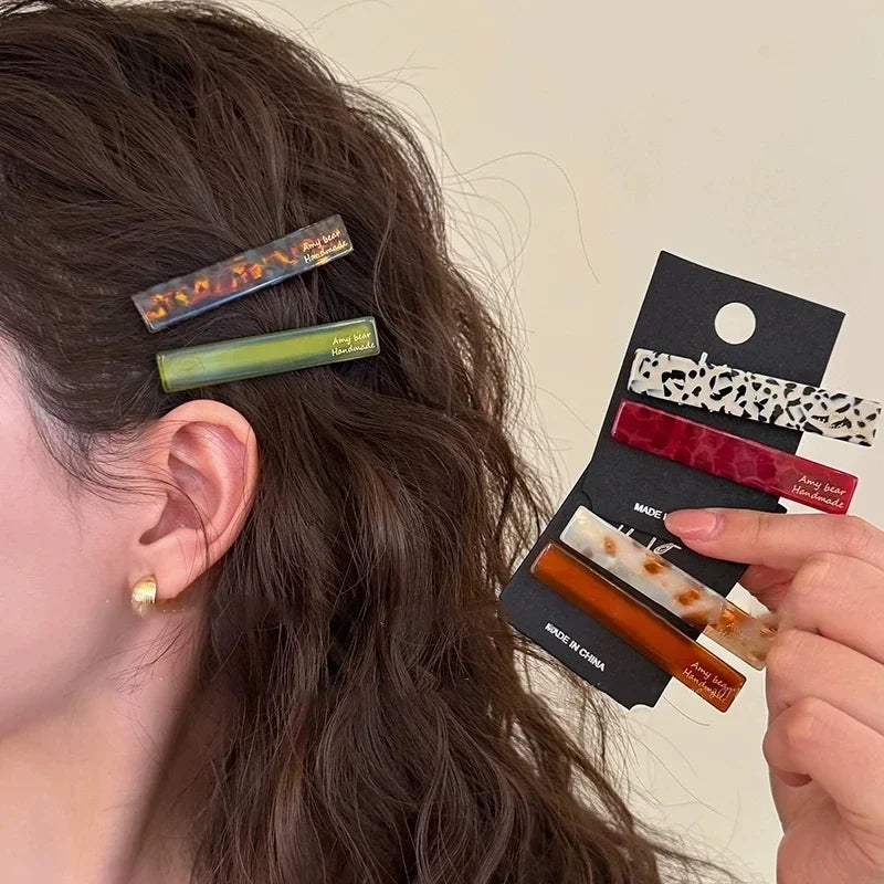 Two geometric clips worn above the ear, with more color pairs on cards