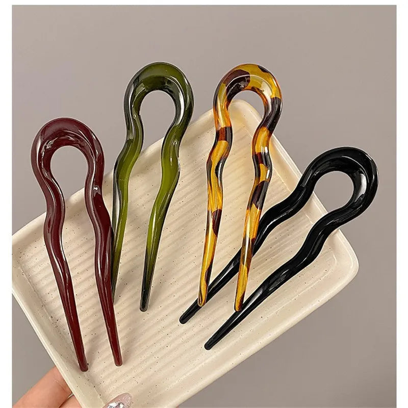 Burgundy, olive green, tortoiseshell-pattern and black French hair pins on a cream tray