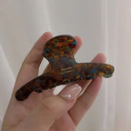 Tortoiseshell-pattern claw clip held in a hand to show its size