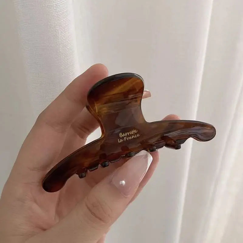 Darker tortoiseshell-pattern claw clip held in a hand