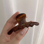 Darker tortoiseshell-pattern claw clip held in a hand