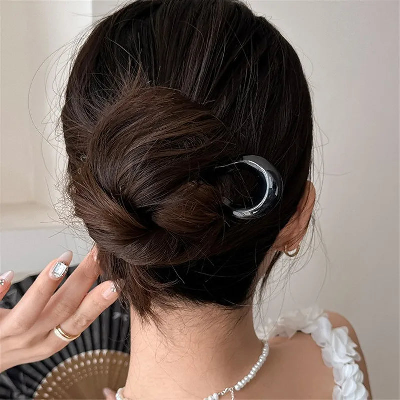 Back view of a low bun held by a black French hair pin
